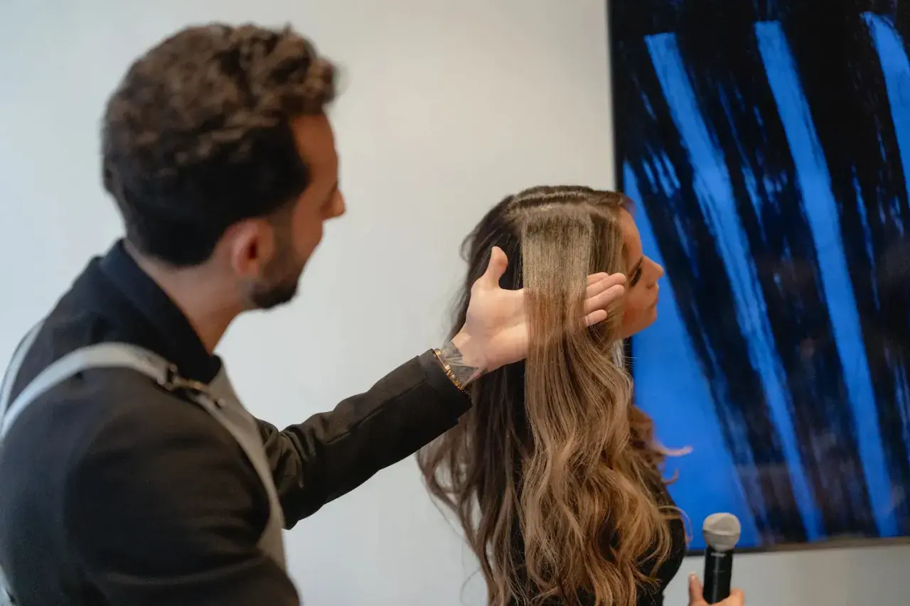 Hombre revisa el pelo elastico de una mujer, mostrando su textura y brillo.