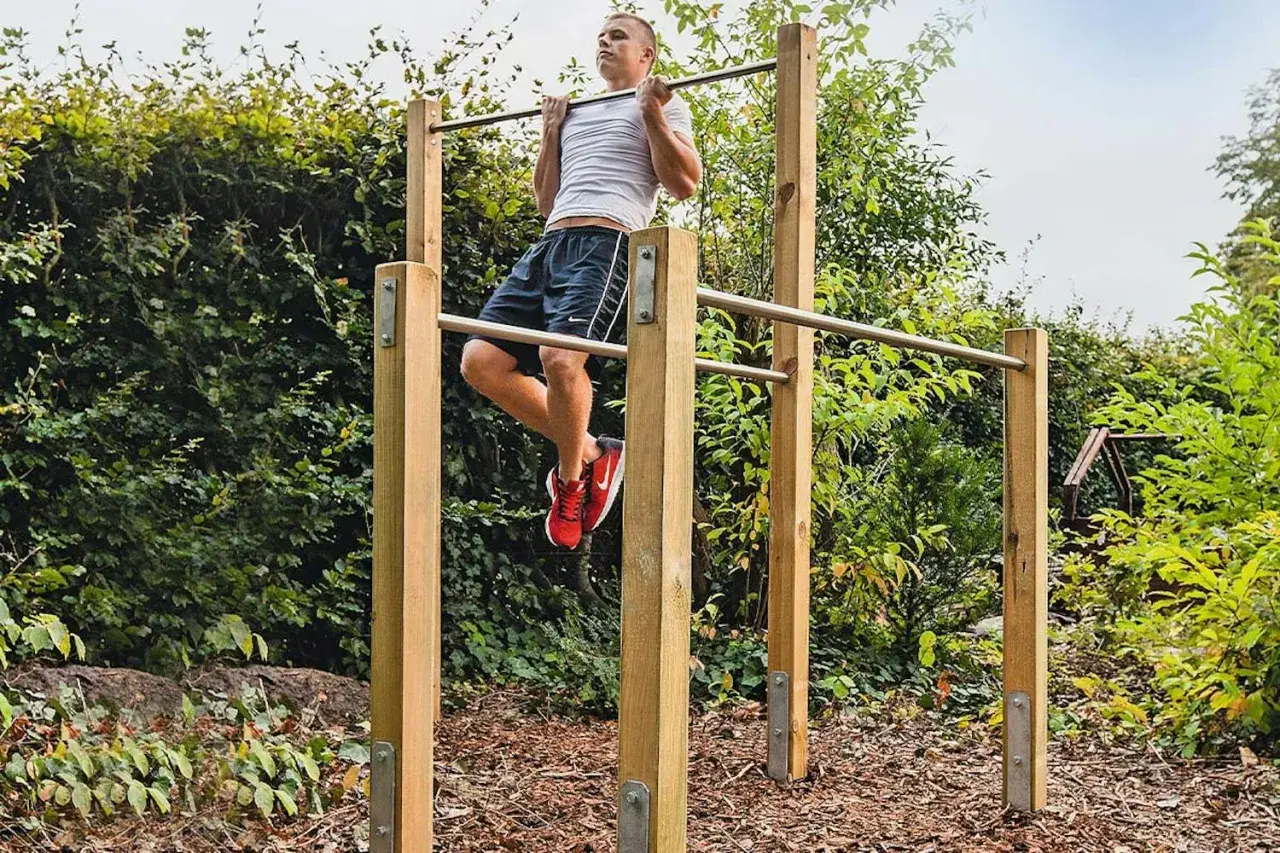 Man tränar pull-ups på ett utegym. Enkla och robusta konstruktioner som inspirerar till att bygga utegym.