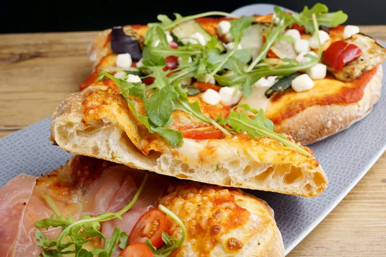 En skiva pizza napoletana med luftig deg, mozzarella, ruccola och prosciutto.