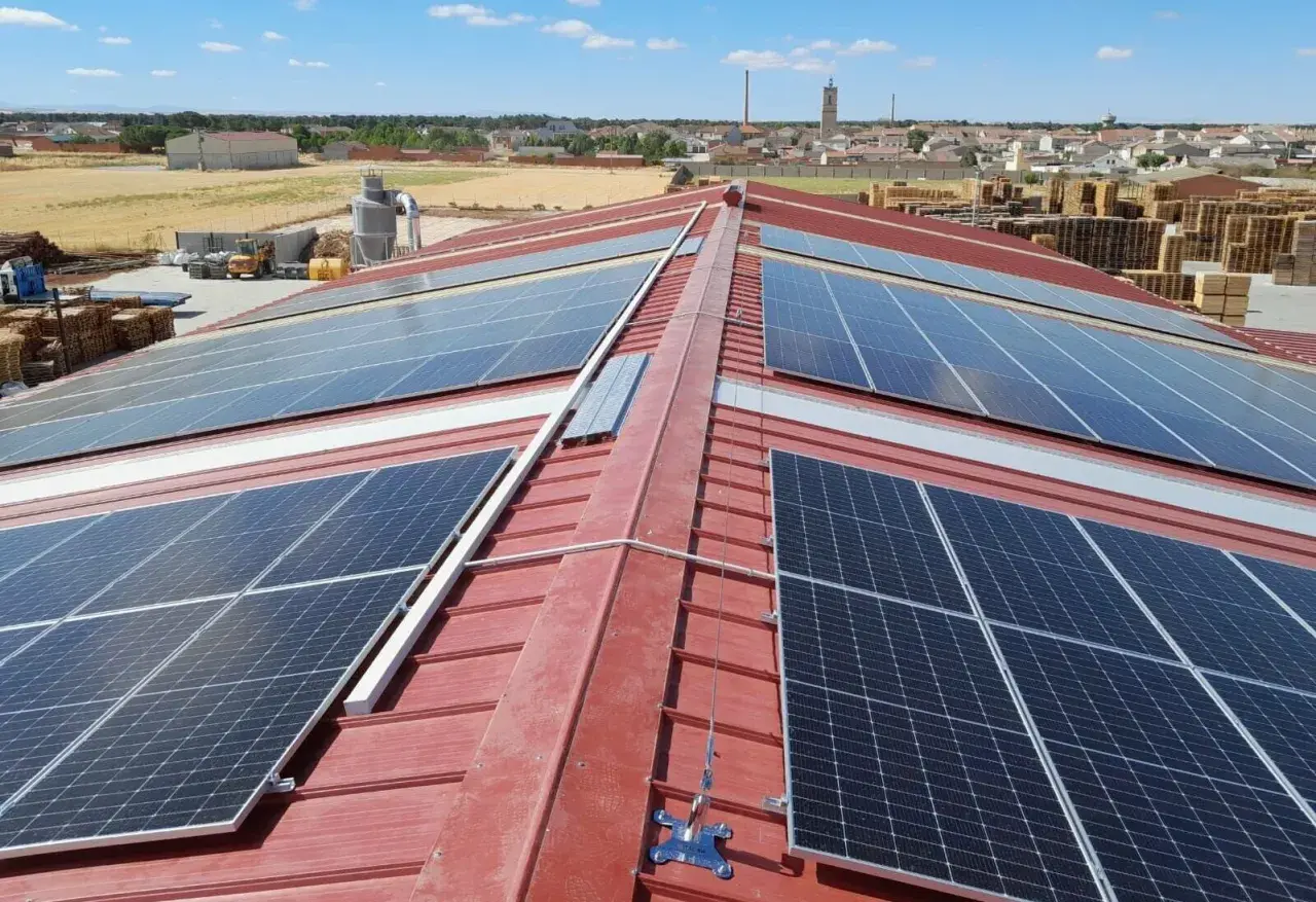 Paneles solares cubren el tejado rojo de un edificio industrial, capturando la energía del sol.