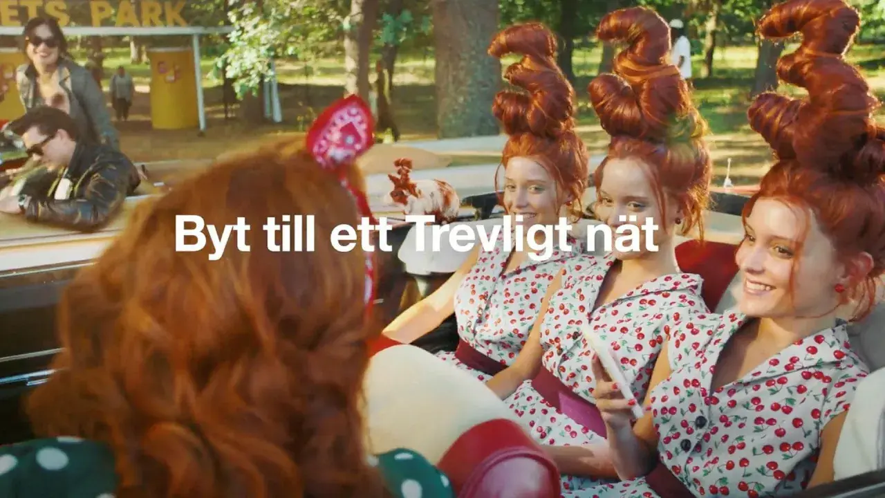 Tre unga kvinnor med fantasifulla frisyrer i en bil. En reklamtext lyder "Byt till ett Trevligt nät".