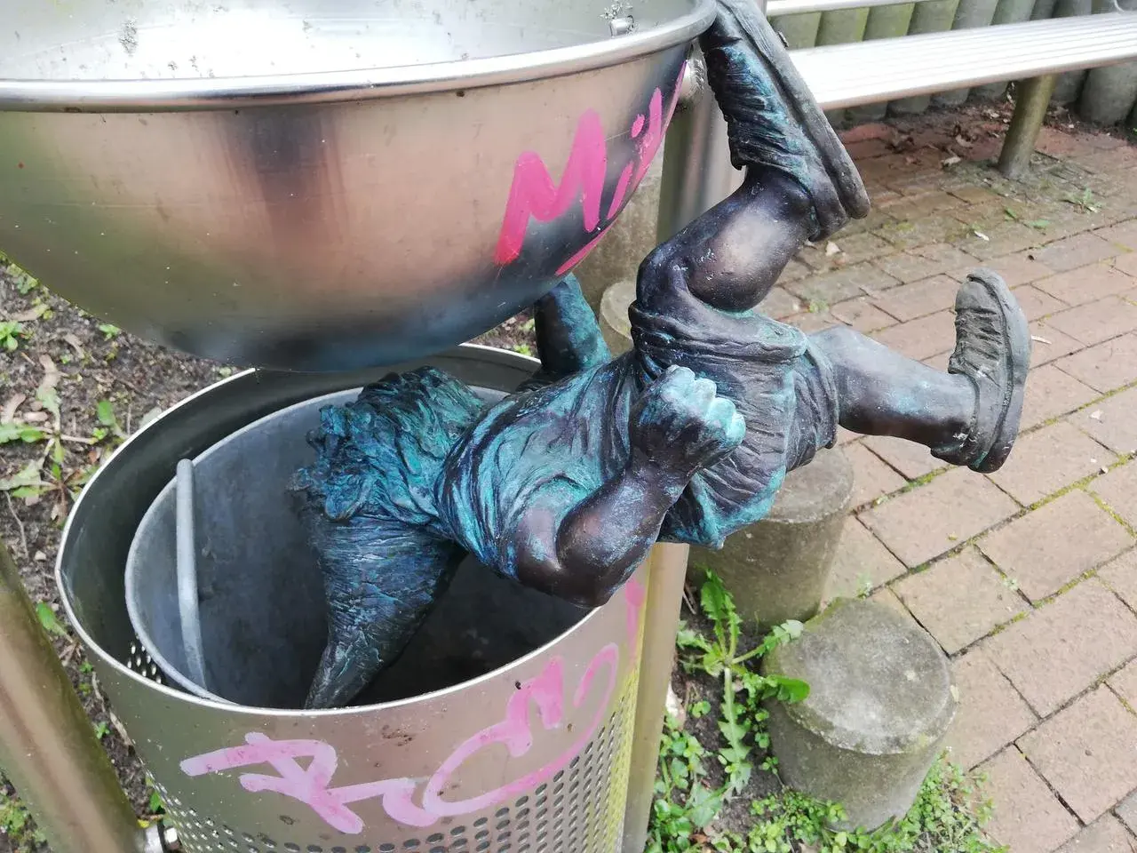 Ein bronzener Zwerg hängt kopfüber in einem Mülleimer in Hitzacker. Die Zwerge sind ein beliebtes Motiv.