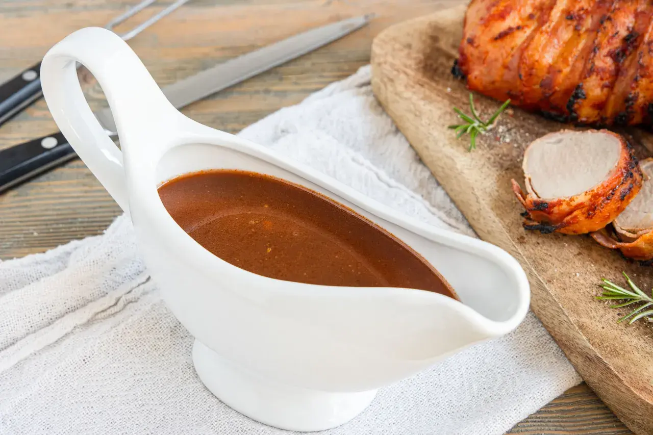 Sternekoch-Qualität: Eine weiße Sauciere mit glänzender Portweinsauce neben einem saftigen Braten.