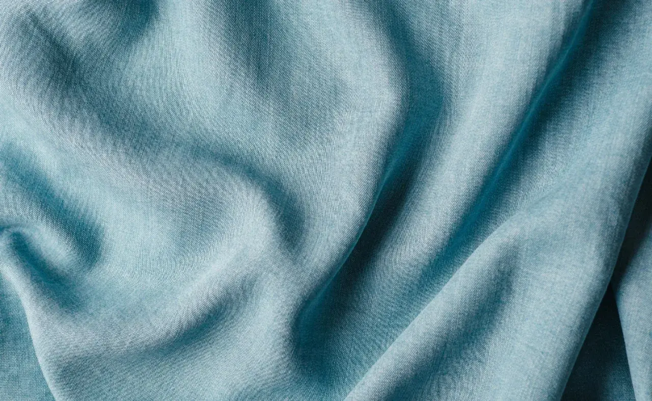 Plissé de textiles artificiels bleu pâle, évoquant la douceur et la fluidité d'une étoffe moderne.