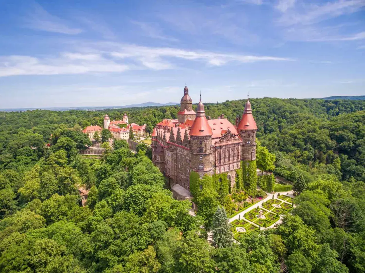 Majestätisches Schloss Kynast, eingebettet in grüne Wälder in Niederschlesien, mit roten Dächern und gepflegten Gärten.