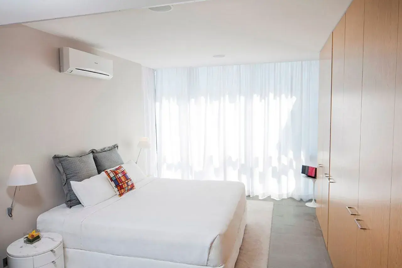 Un dormitorio moderno con aire acondicionado en la pared, ideal para saber donde colocar el aire acondicionado en un dormitorio.