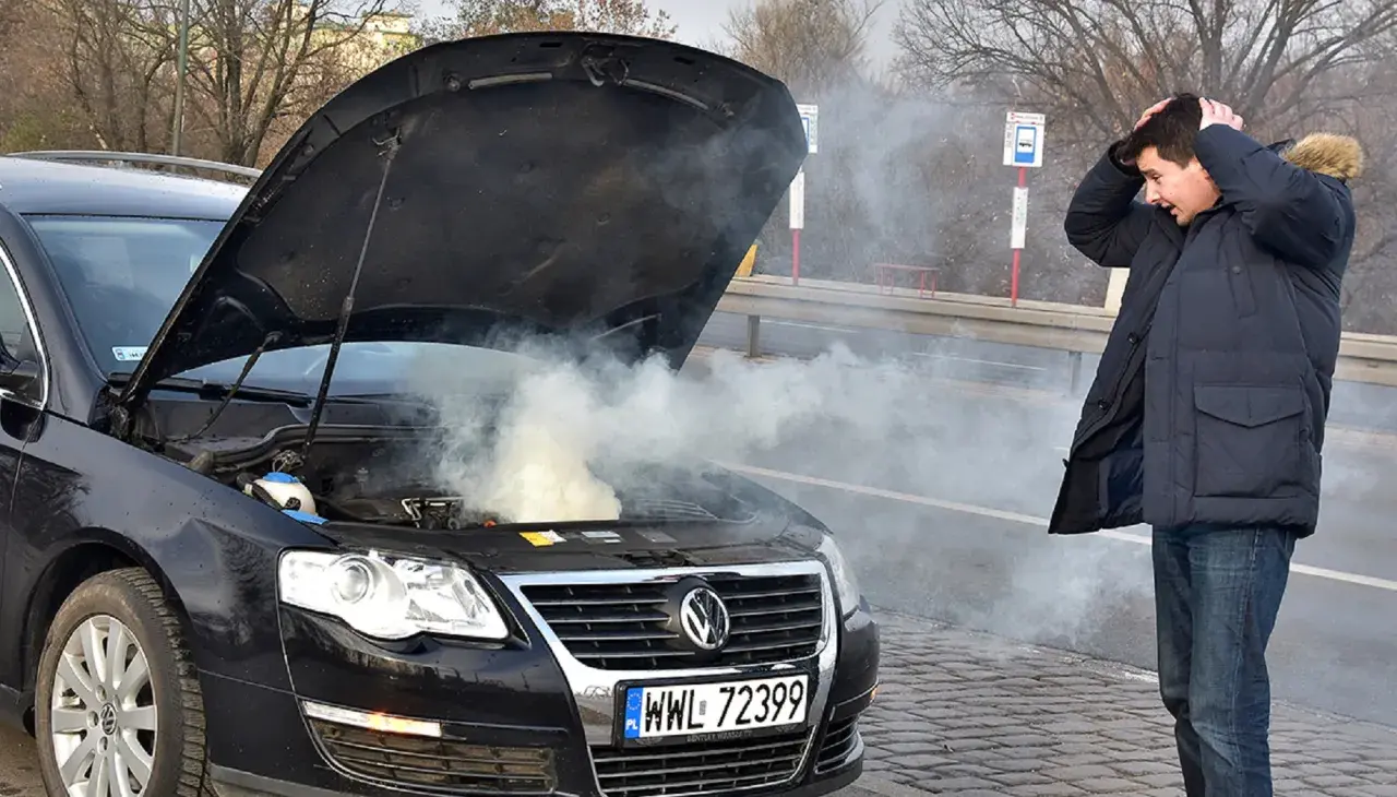 Zmartwiony kierowca przy dymiącym silniku. Zastanawia się, ile kosztuje wyjęcie silnika z samochodu po awarii.