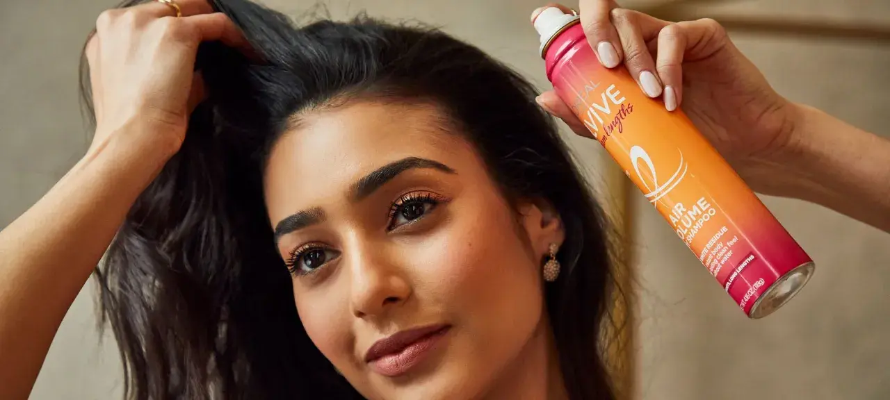 Mujer usa spray para disimular pelo sucio, dándole volumen y frescura al instante.