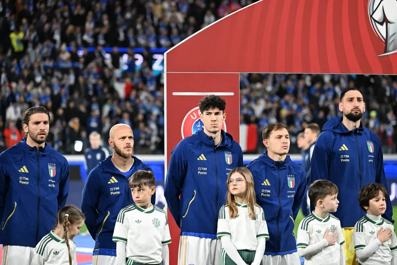 Piłkarze Włoch i Serbii stoją w rzędzie, dzieci w strojach kibicują.