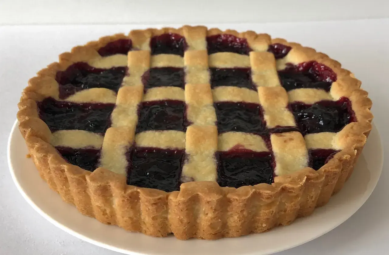 Una deliziosa crostata di marmellata con una griglia di pasta dorata e un ripieno scuro e invitante.