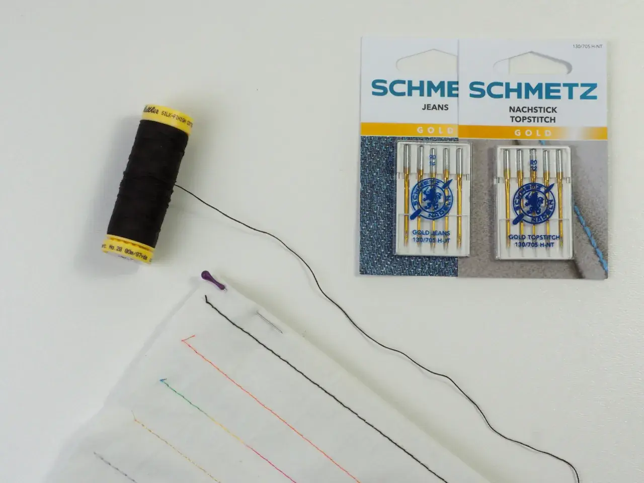 Schwarzer faden zum reparieren von kleidung, Nadeln und Stoff mit bunten Stichproben.