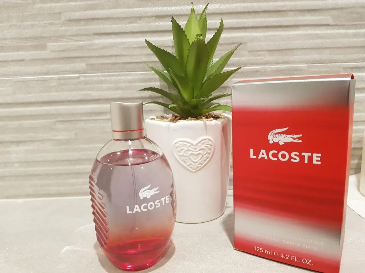 Perfumy męskie Lacoste Red 125ml w szklanej butelce obok czerwonego kartonika.