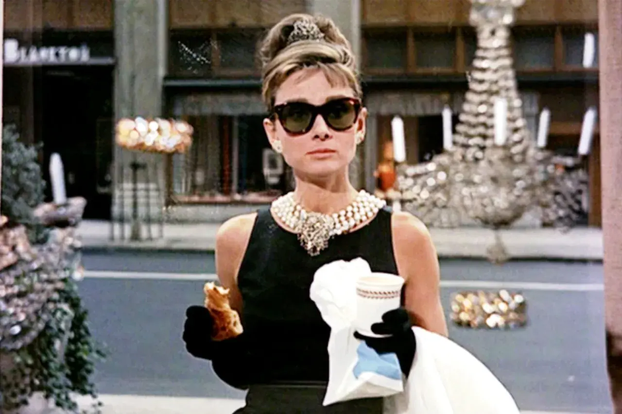 Holly Golightly, icona di stile, gusta un croissant davanti a Tiffany. Le sue recensioni su "Colazione da Tiffany" sarebbero sicuramente positive!