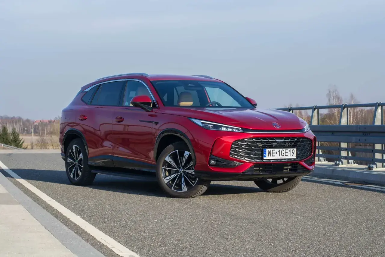 Czerwony MG HS Hybrid na drodze, z widocznym grillem i światłami LED. Elegancki SUV gotowy na podróż.