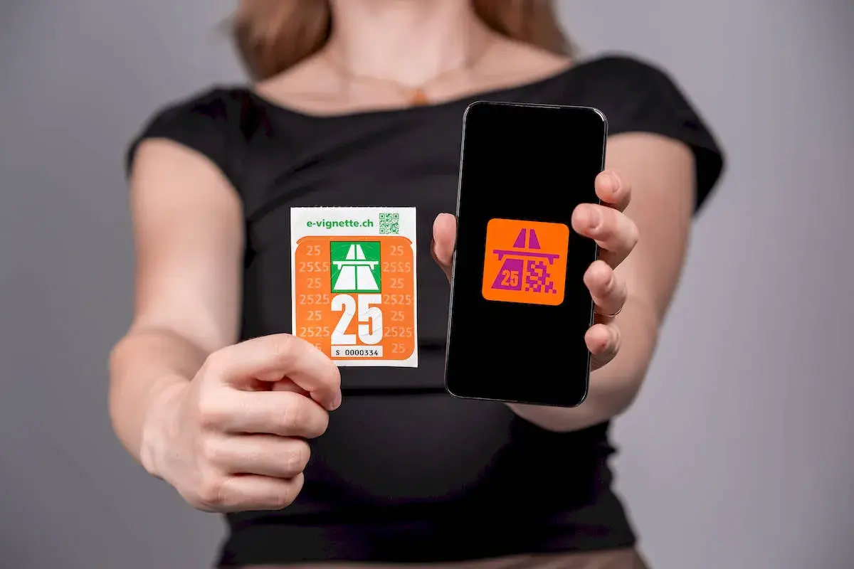 Elektroniczna winieta na szwajcarskie drogi płatne i jej cyfrowy odpowiednik na ekranie smartfona.