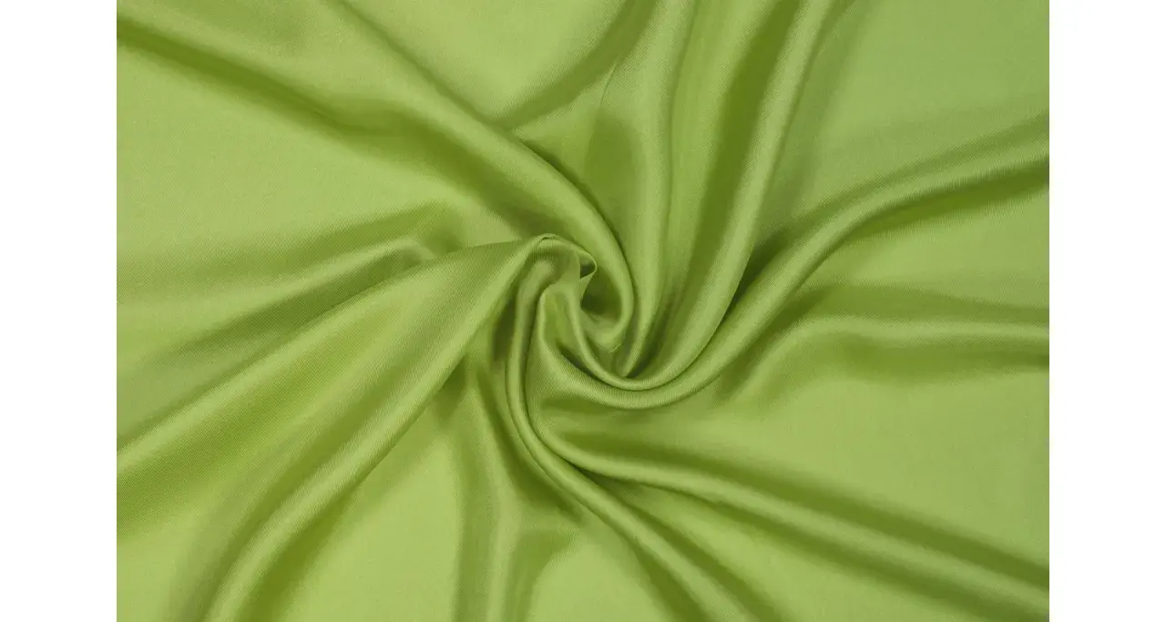 Drapé de tissu sergé vert pomme, doux et soyeux, formant des plis élégants.