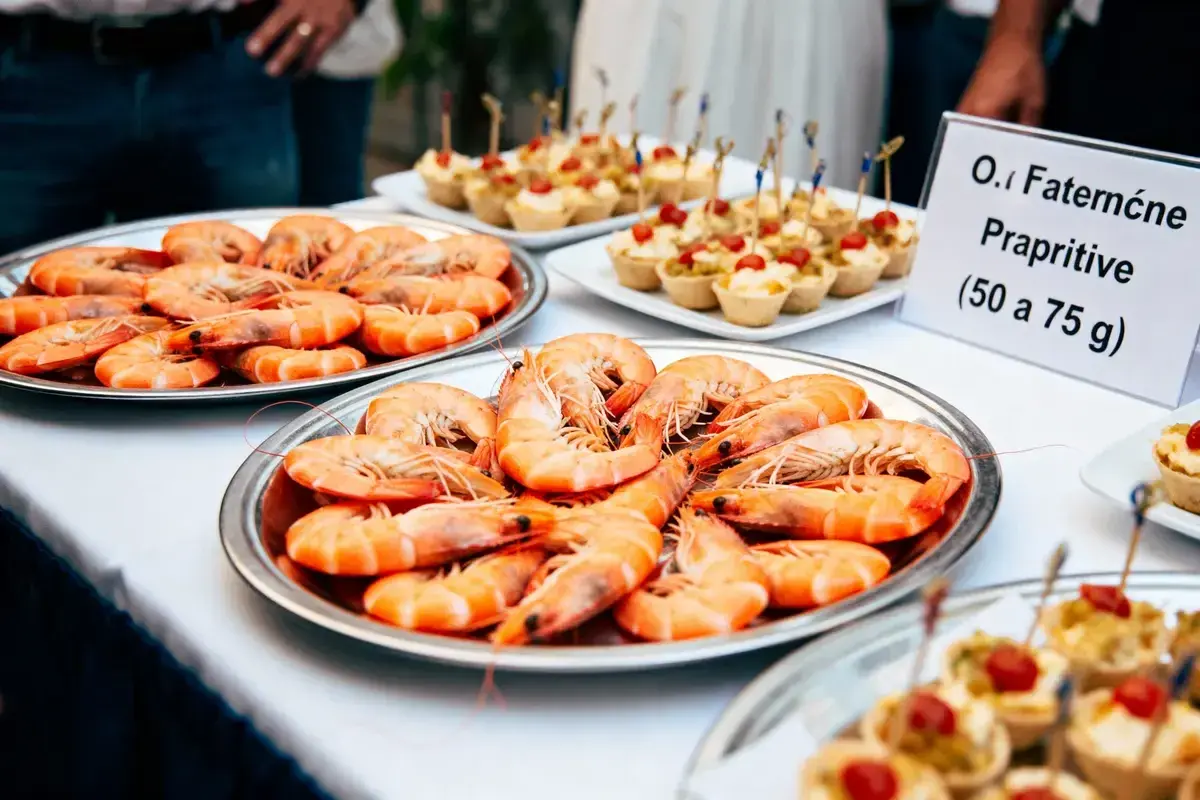 Plateaux de crevettes pour un buffet. Une pancarte indique "O.I Faterne Prapriitive (50 a 75 g)", suggérant combien de crevettes par personne.