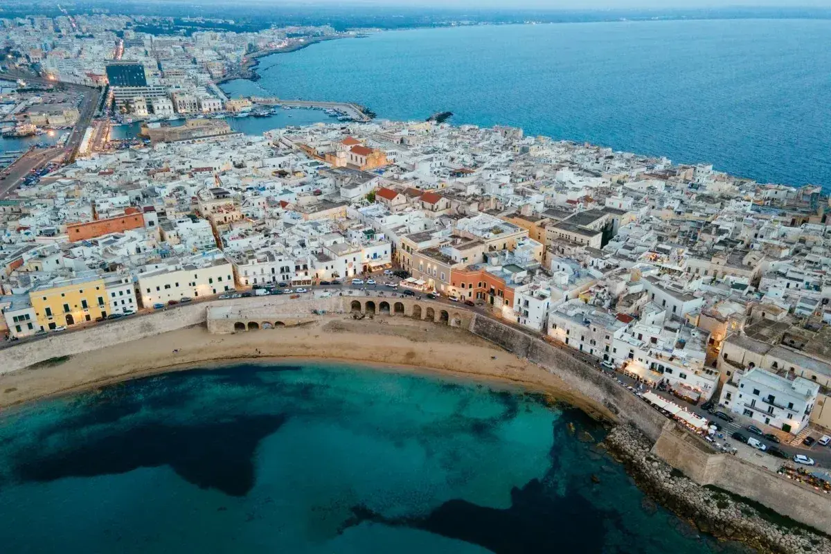 Gallipoli vecchia: un labirinto di vicoli bianchi che si affacciano sul mare turchese, con un'antica muraglia che abbraccia la costa.
