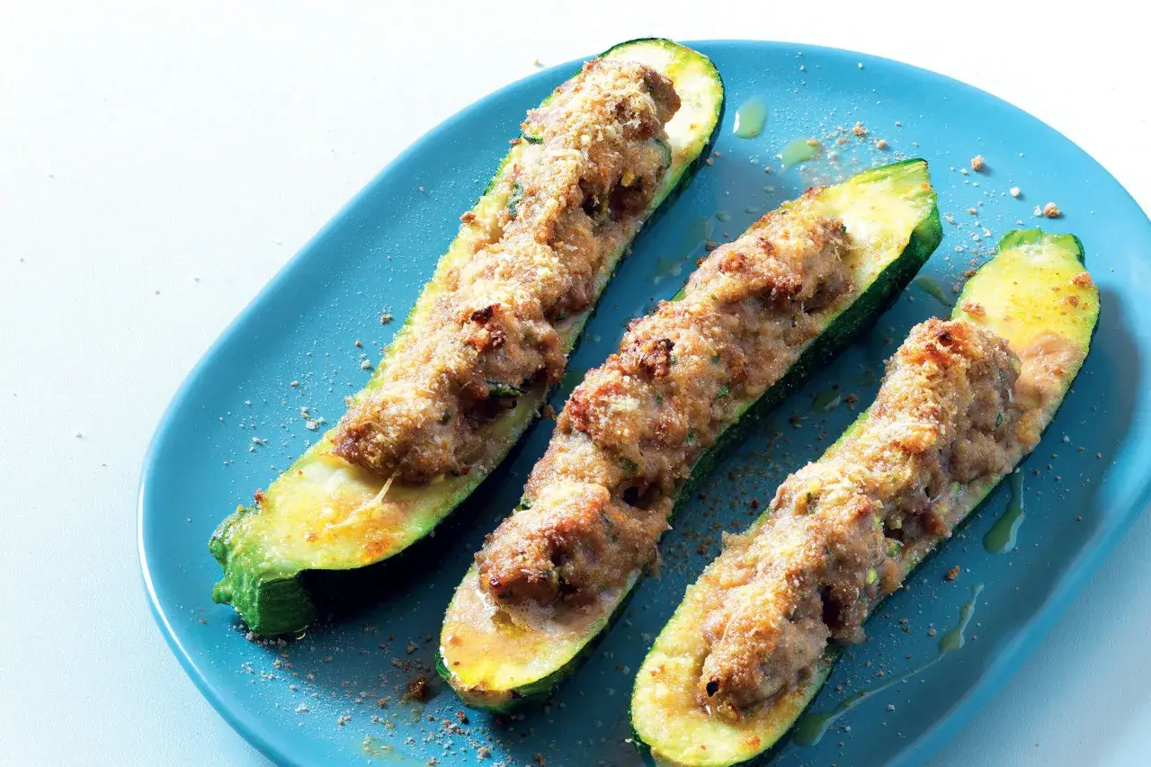 Tre zucchine ripiene velocissime, dorate e appetitose, servite su un piatto blu.