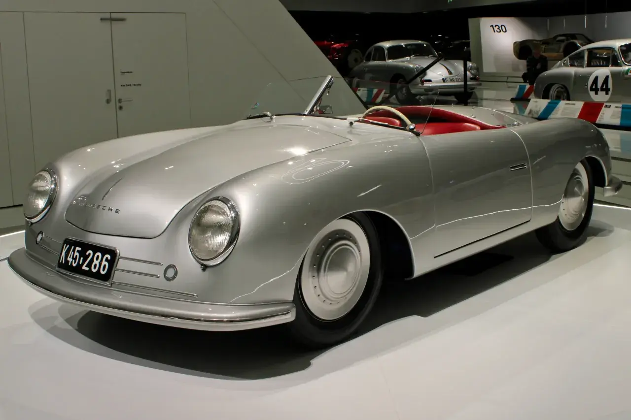Srebrny kabriolet Porsche 356 z czerwonym wnętrzem, prezentowany na wystawie.