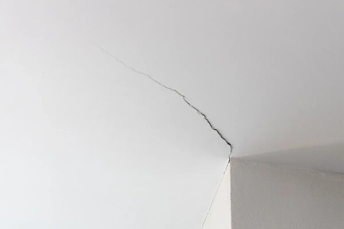 Fissure sur un plafond blanc, signe d'une trame de renovation nécessaire.