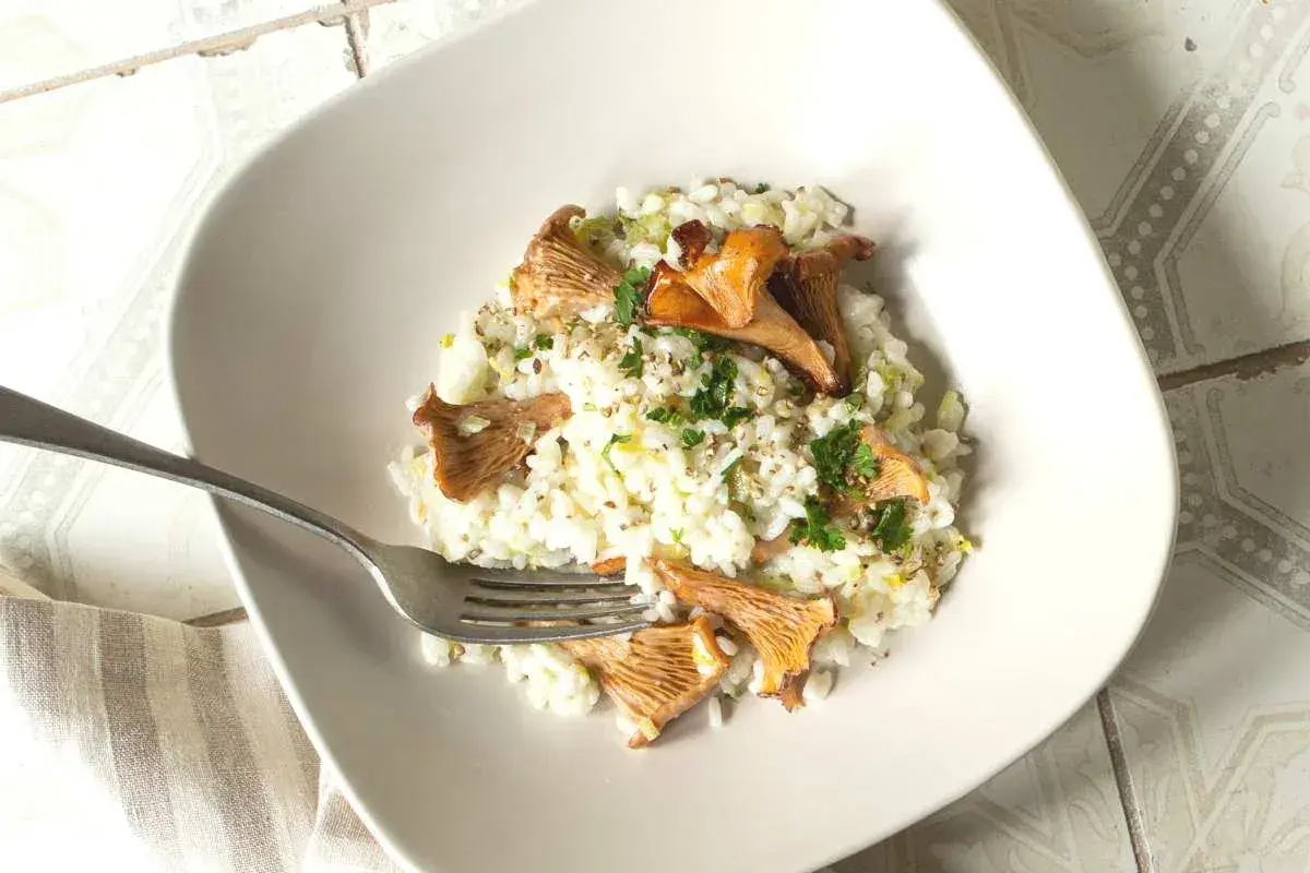 Un crémeux risotto aux girolles, parsemé de persil frais et d'un peu de poivre. Un délice simple et savoureux.