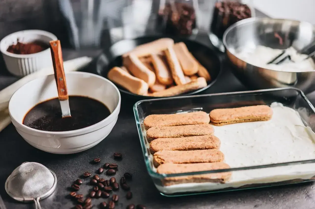 Przygotowanie tiramisu w ciąży: biszkopty maczane w kawie, krem i kakao. Pyszny deser dla przyszłej mamy.