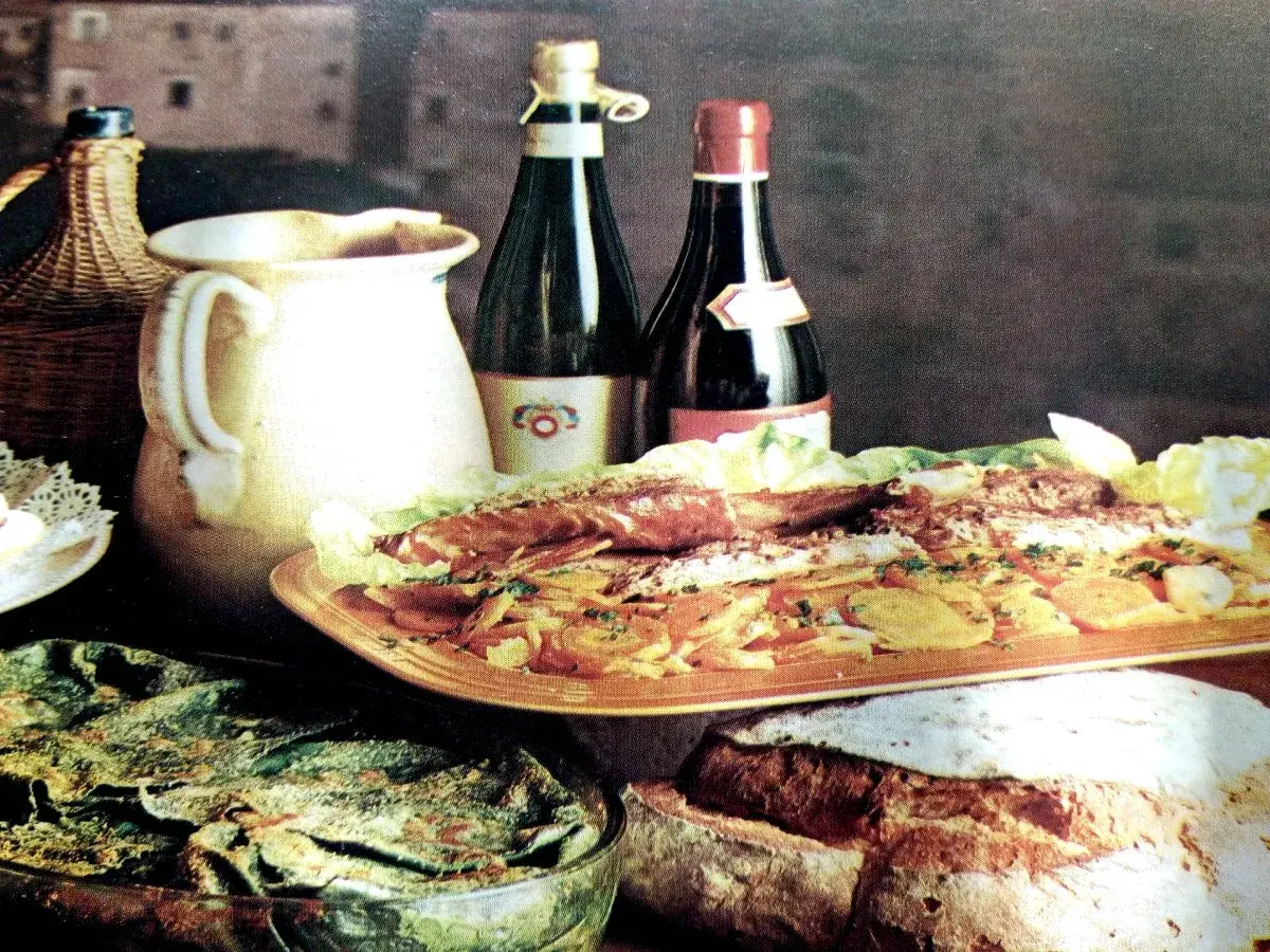 Un banchetto con pesce, verdure e pane fresco, accompagnato da vino e brocca. Sapori autentici del **chilometro zero Rodi Garganico**.