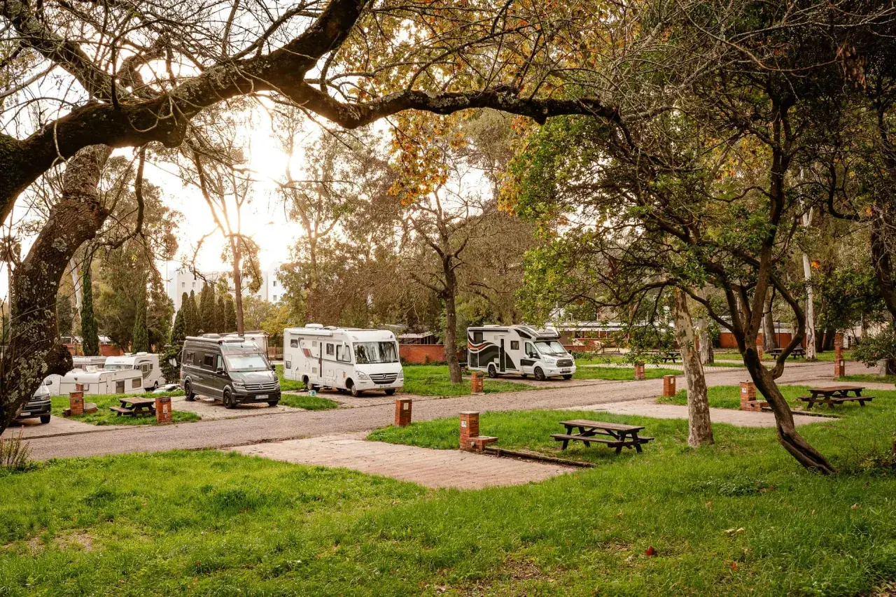 Autocaravanas y furgonetas aparcadas en un camping cerca de Lisboa, bajo la luz dorada del atardecer.