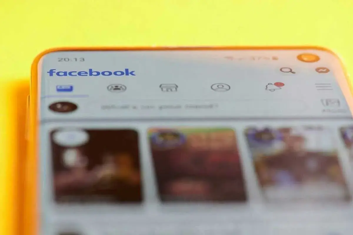 Telefon z otwartą aplikacją Facebook. Widoczny pasek wyszukiwania i ikony powiadomień. Dowiedz się, jak znaleźć swoje relacje na Facebooku.