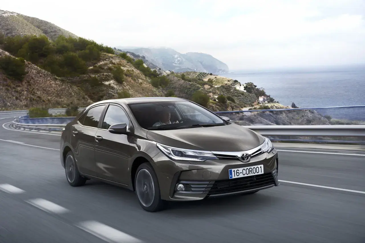 Brązowa Toyota Corolla 2017 jedzie krętą drogą nad morzem.