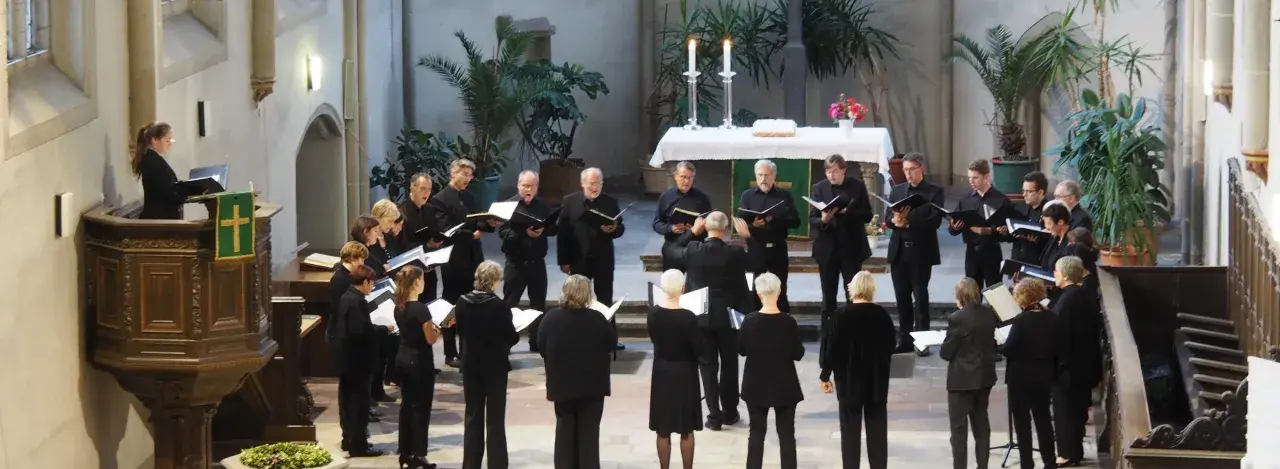 Chor singt in Kirche. Ein Dirigent leitet. Hier finden Sie kirchenmusik stellenangebote.
