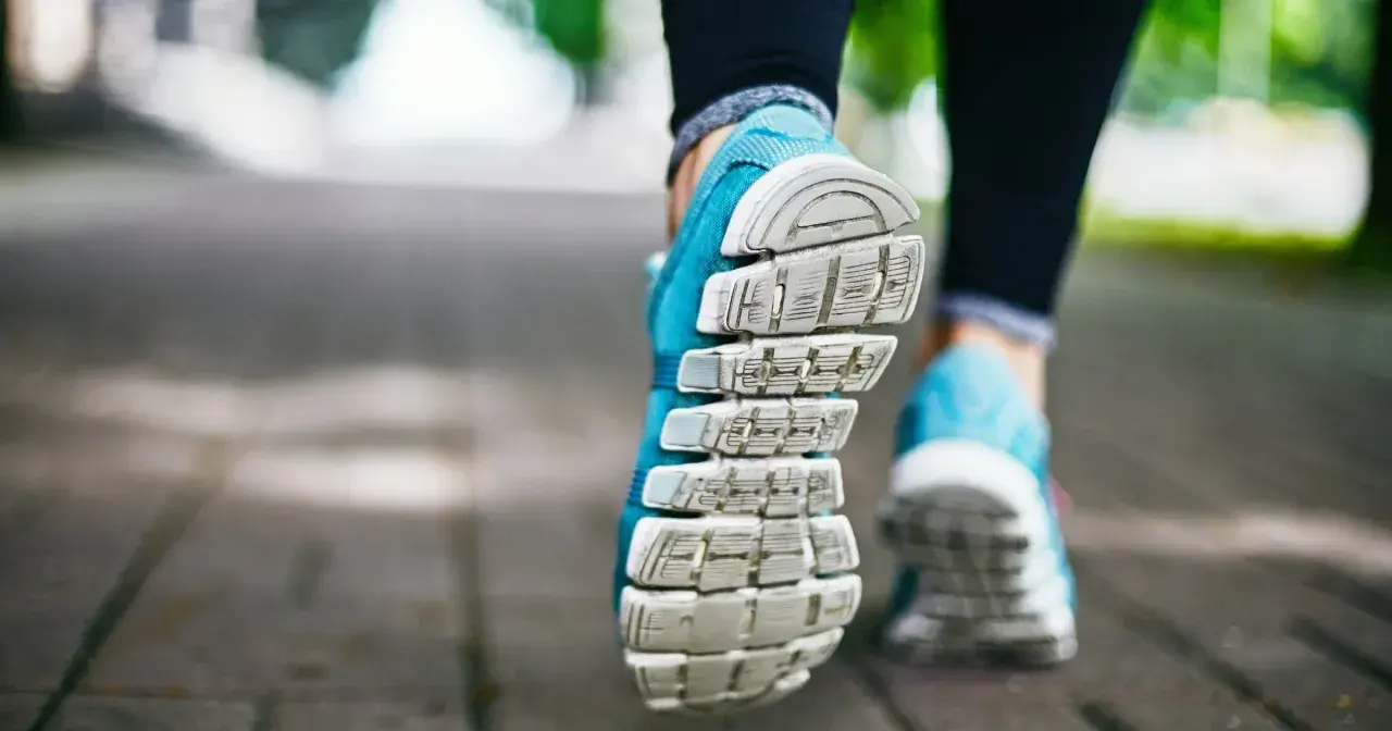 Niebieskie buty sportowe na chodniku, gotowe na szybki marsz czy bieganie.