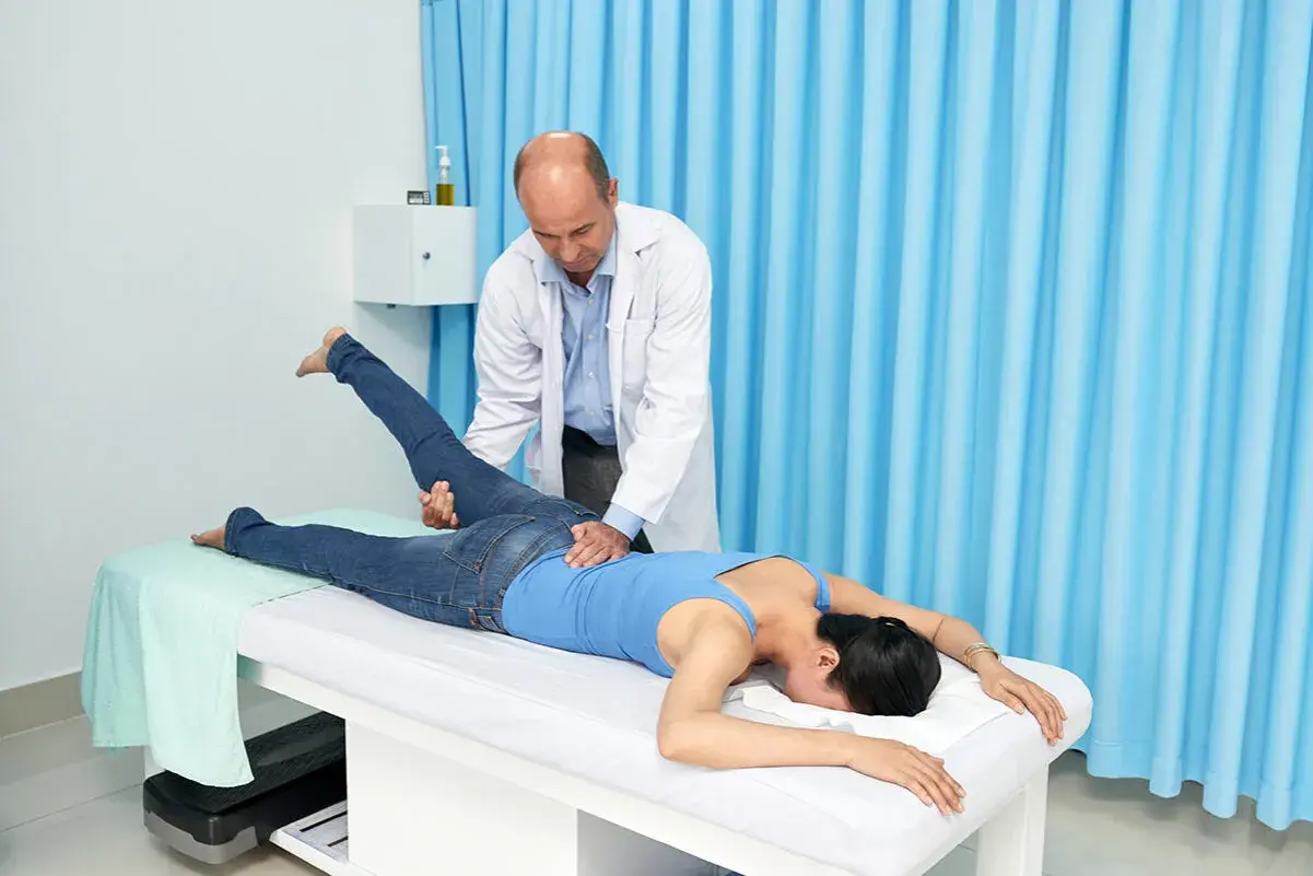 Fizjoterapeuta wykonuje test Mennella na pacjentce leżącej na kozetce.