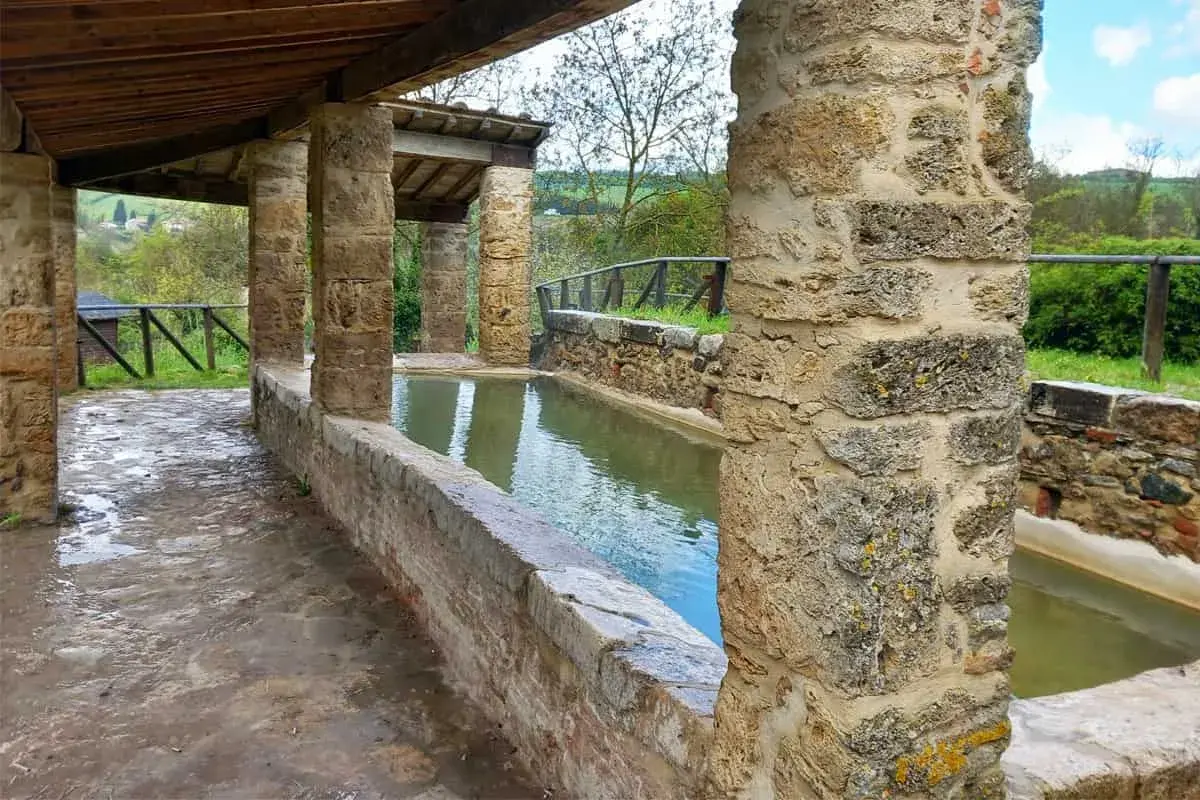 Antiche vasche d'acqua nel centro storico di San Casciano dei Bagni, con colonne in pietra e tettoia in legno.