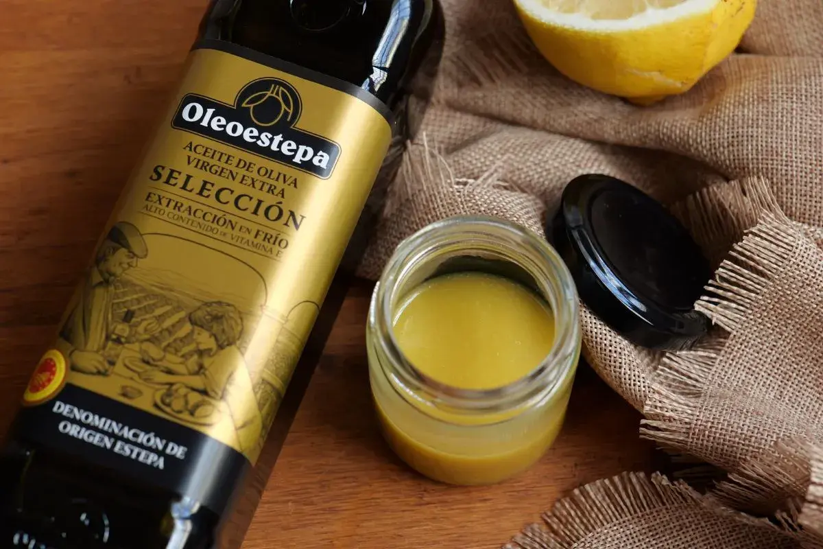 Ingredientes para una vinagreta de mostaza: botella de aceite de oliva virgen extra, un tarro con la vinagreta y un limón.