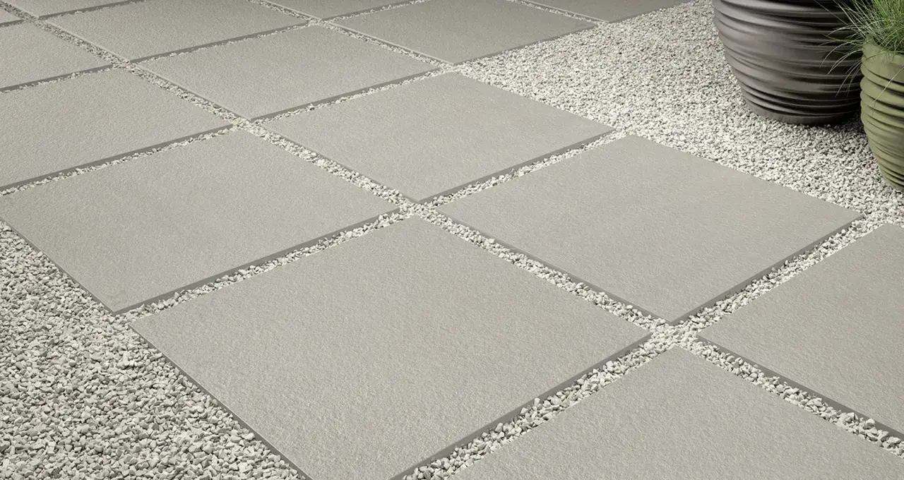 Posa a secco su ghiaia: lastre quadrate grigie alternate a ghiaietto bianco creano un percorso moderno e pulito.