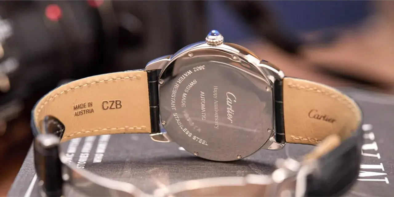Reloj Cartier con grabado "Happy Anniversary", automático, acero inoxidable, hecho en Suiza. La correa de cuero indica "Made in Austria".