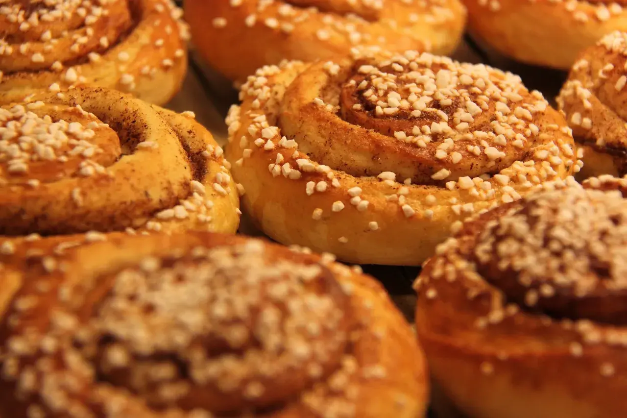 En närbild på nybakade kanelbullar, perfekta för kanelbullens dag. Strösslade med pärlsocker och kanel.