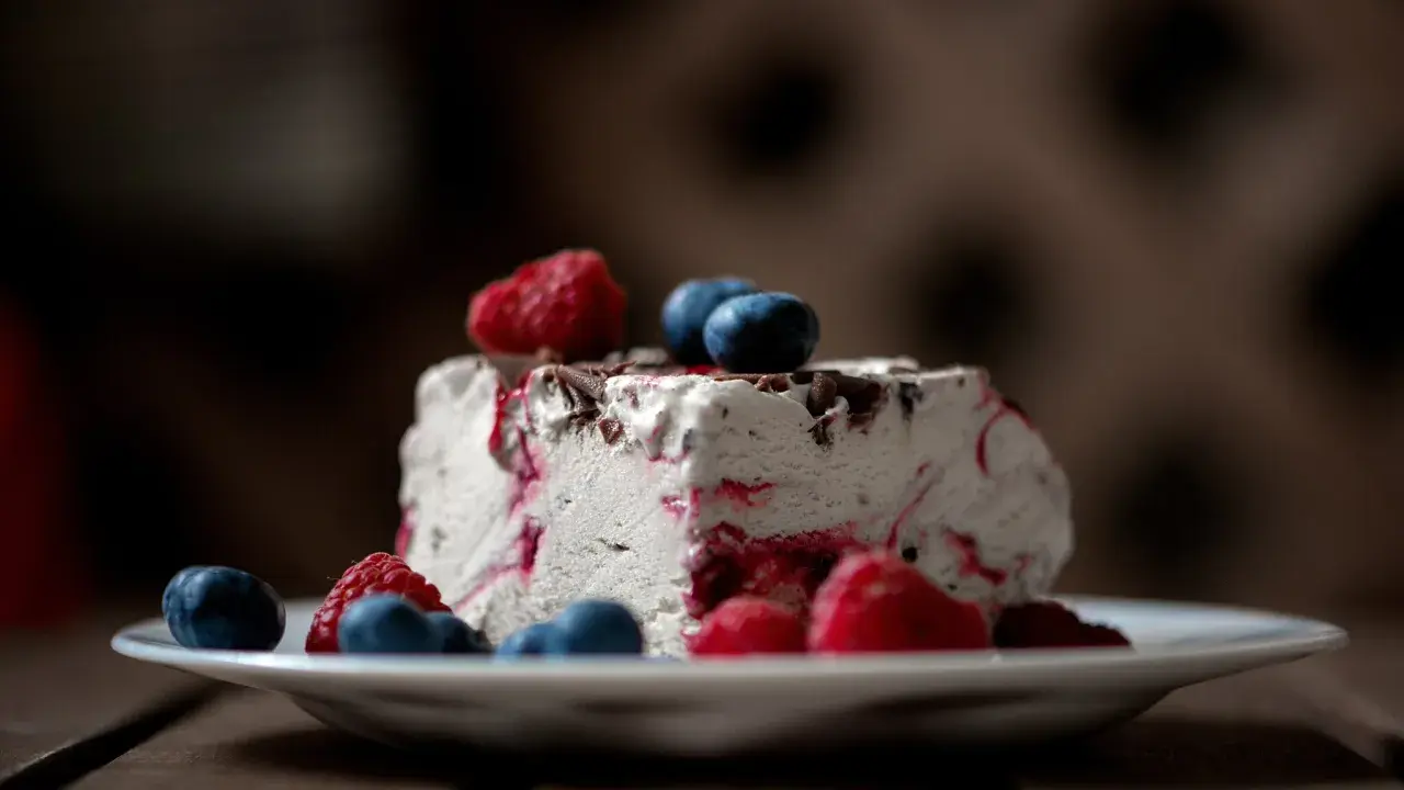 Ein Stück Eistorte mit Beeren und Schokostückchen, perfekt für ein einfaches Eistorte Rezept.
