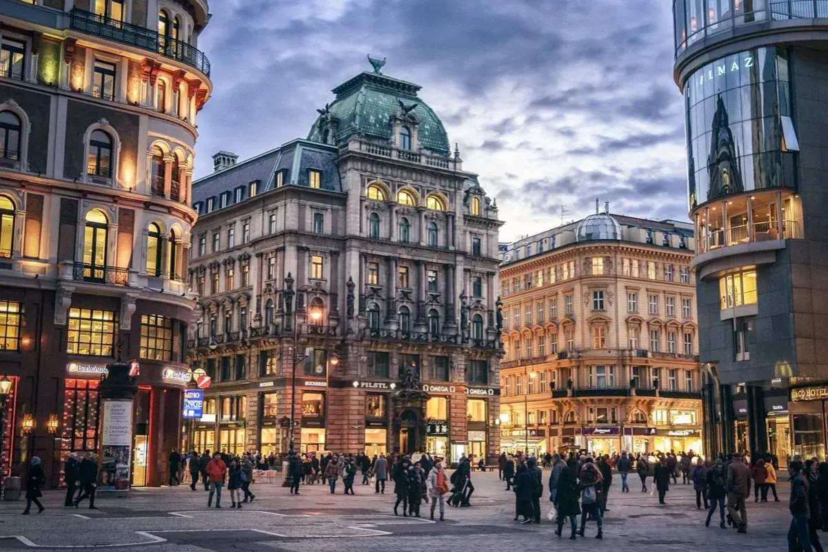 Gente paseando por una plaza en Viena, con edificios históricos y modernos. Ideal para un **free tour Viena**.