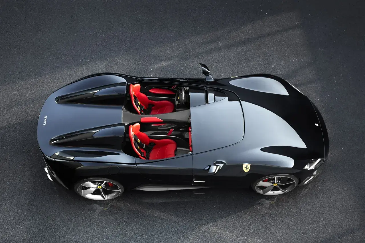 Czarny Ferrari Monza SP2 z czerwonymi siedzeniami, gotowy do jazdy po torze.