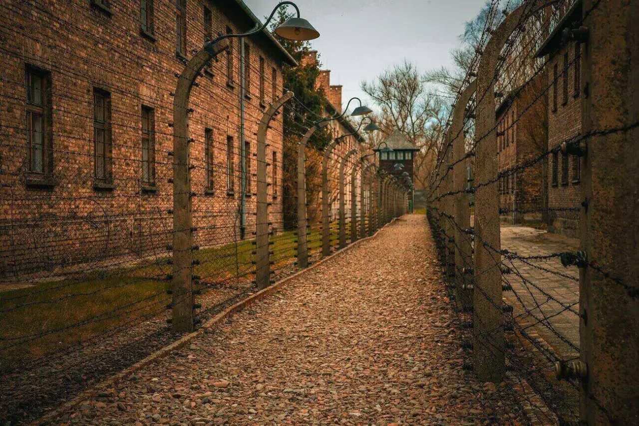 Ścieżka w Auschwitz, gdzie jest, prowadzi między ceglanymi budynkami i drutem kolczastym.