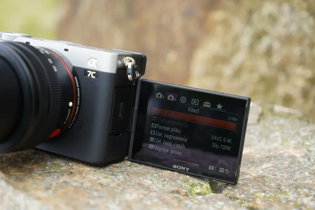 Aparat Sony a7c z obiektywem, na ekranie widoczne menu filmowania z ustawieniami XAVC S 4K.