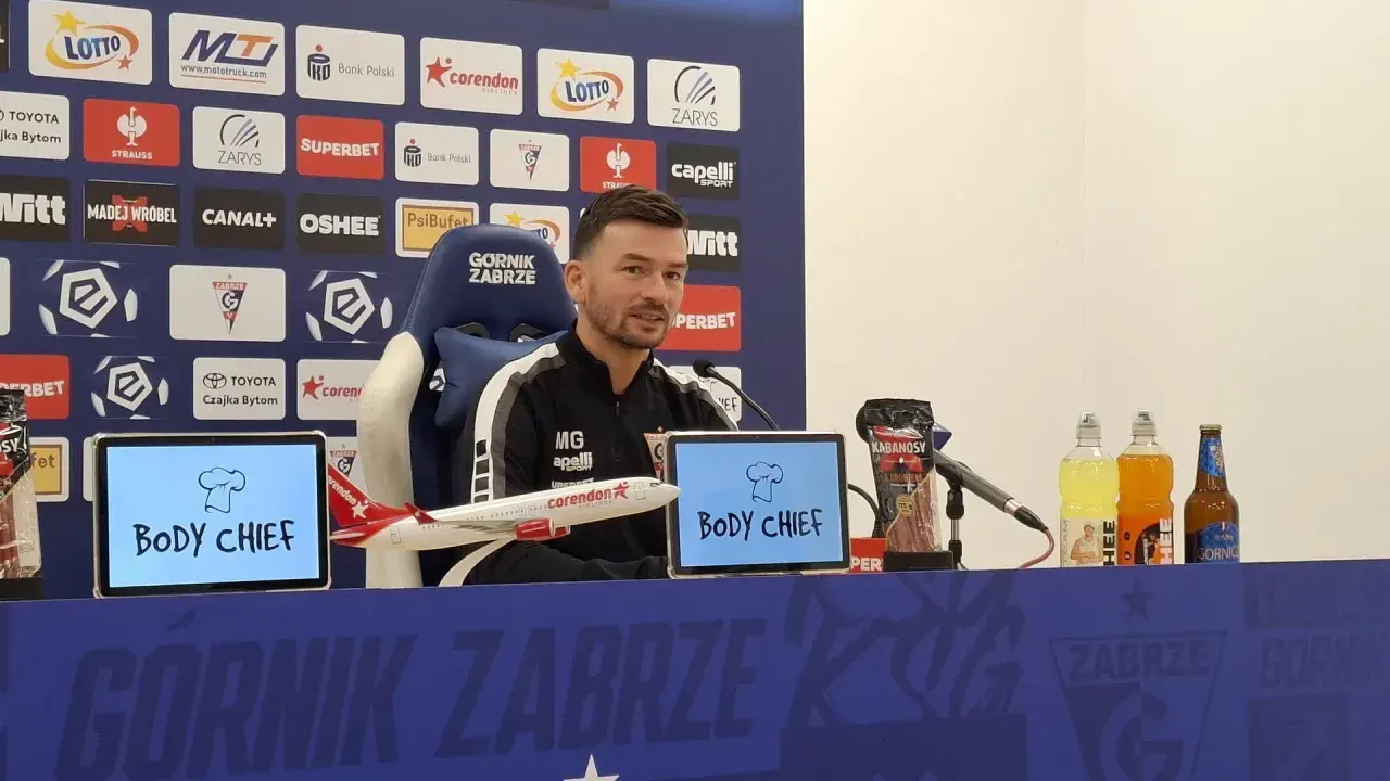 Trener Górnika Zabrze przed meczem z Rakowem Częstochowa. Na stole kabanosy, napoje i model samolotu.