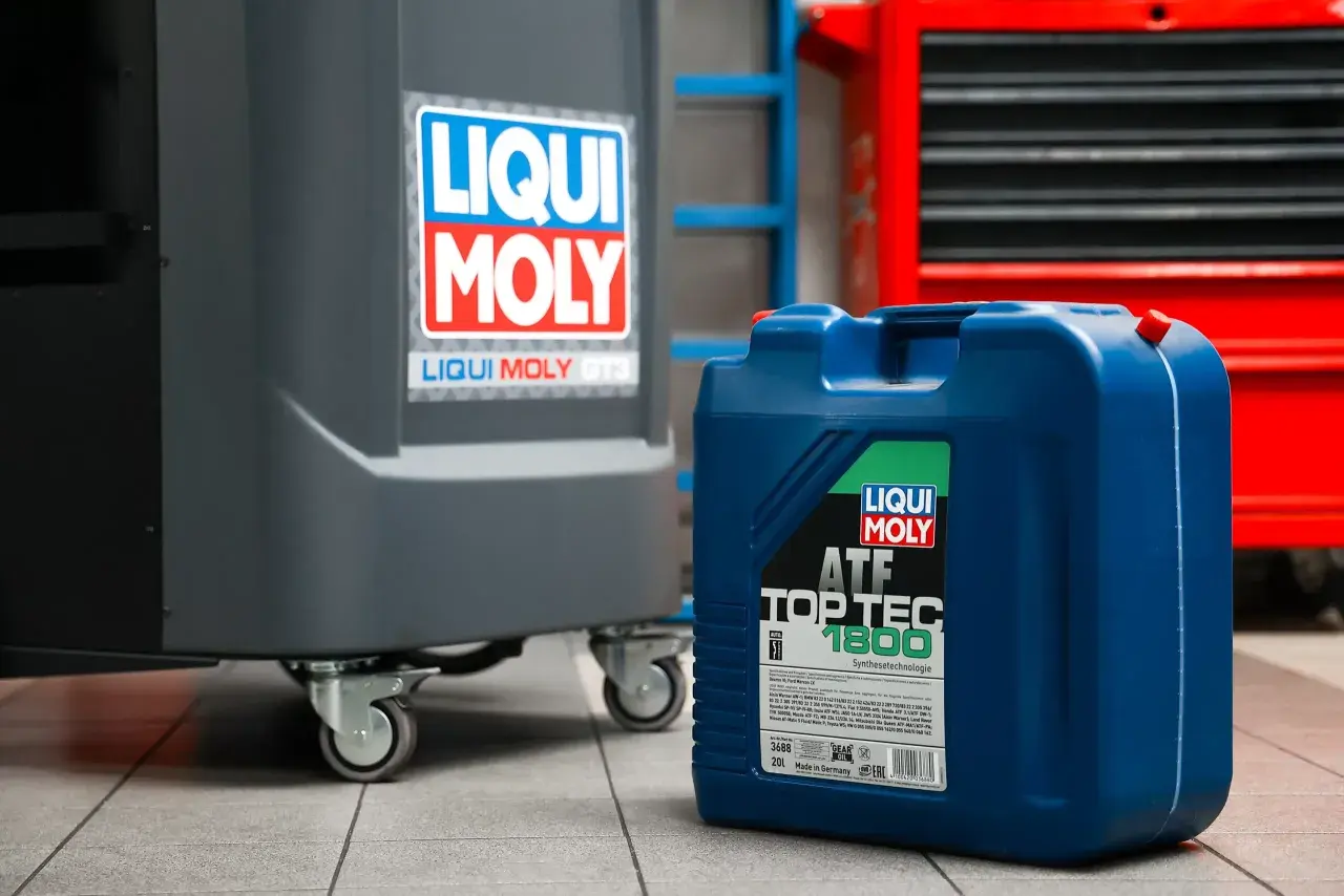 Niebieski kanister z olejem Liqui Moly ATF Top Tec 1800 w warsztacie. Zastanawiasz się, ile bierze mechanik za wymianę oleju?