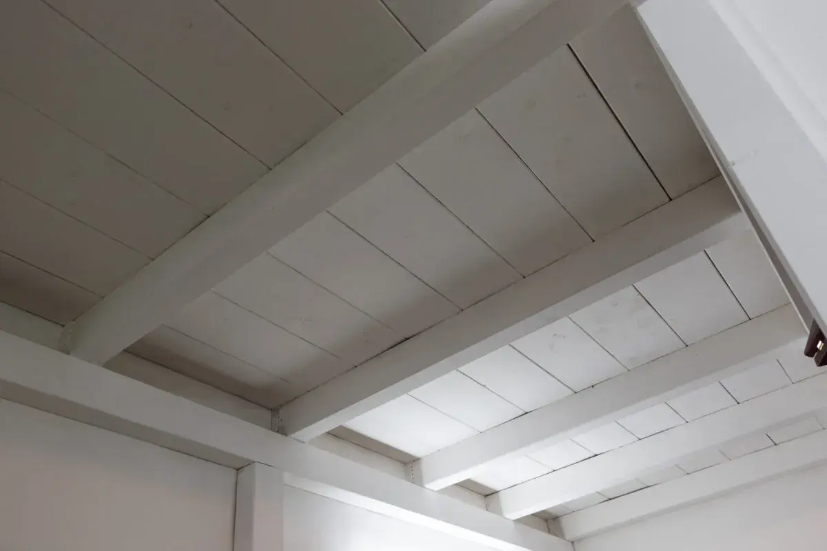 Deckenbalken und Holzpaneele, frisch weiß gestrichen, erhellen den Raum.