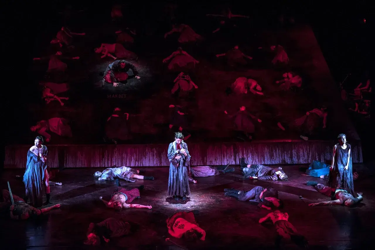 Scena z "Makbeta" w Teatrze Muzycznym Wrocław. Na scenie leżą martwi, stoi postać z dzieckiem.