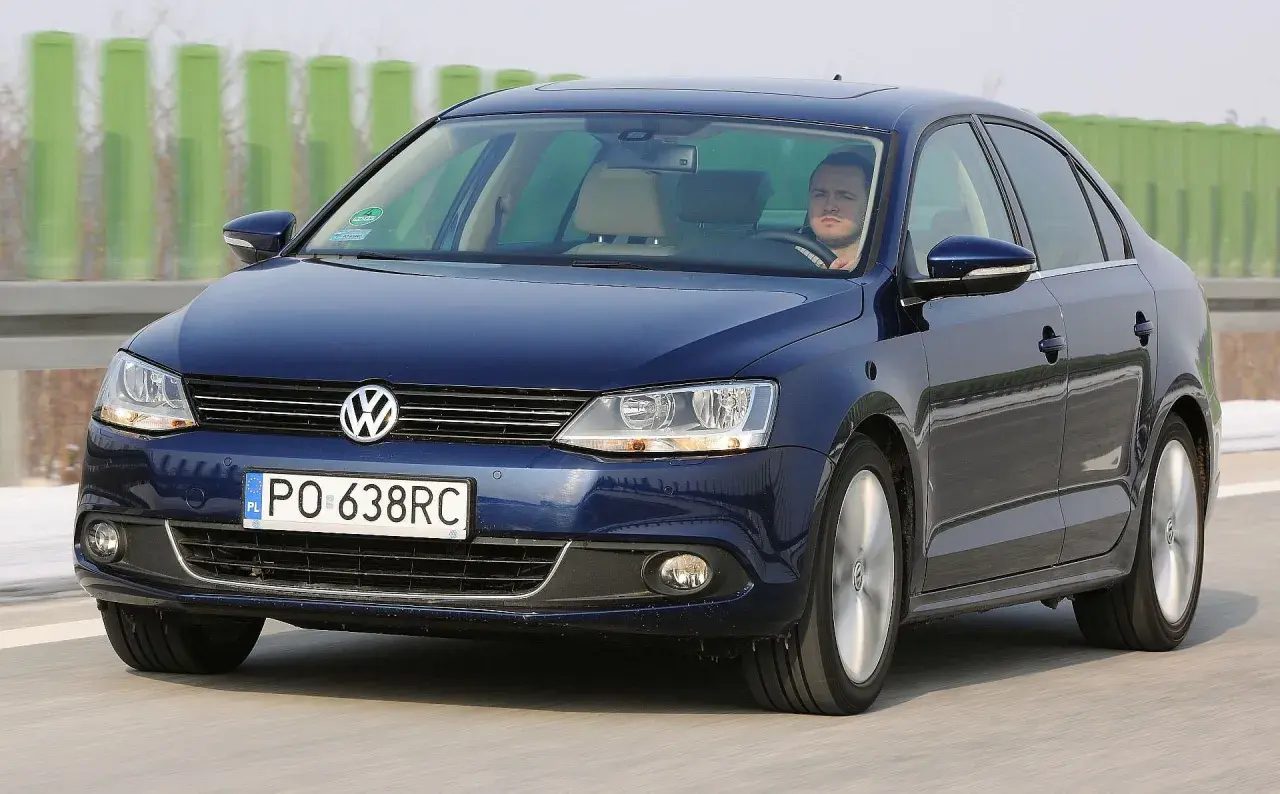 Ciemnoniebieski VW Jetta MK6 jedzie autostradą. Za kierownicą siedzi mężczyzna.