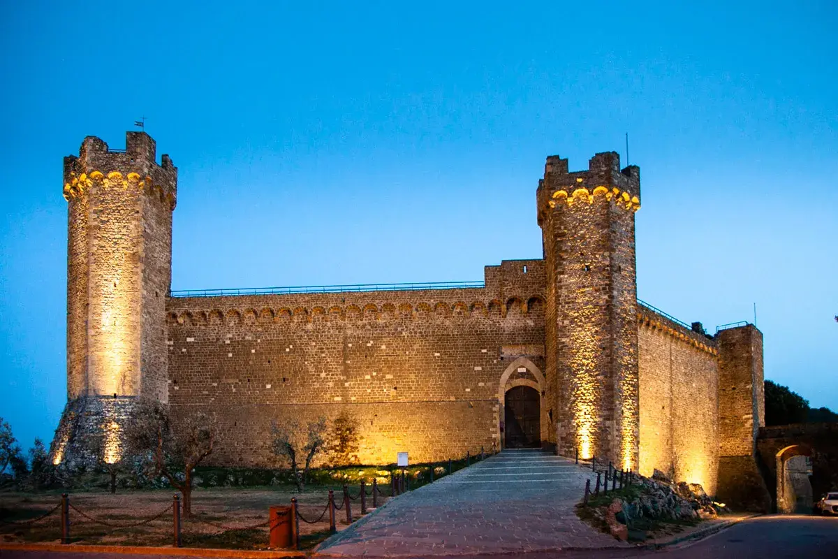 Fortezza illuminata al crepuscolo, un invito a visitare Montalcino e scoprire la sua storia.